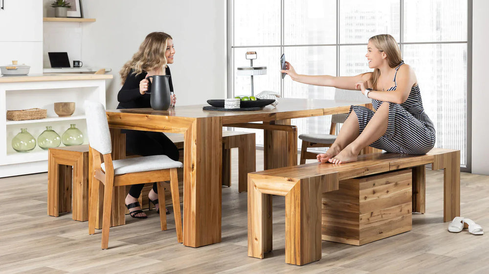 Two friends sitting at a multifunctional table drinking wine.