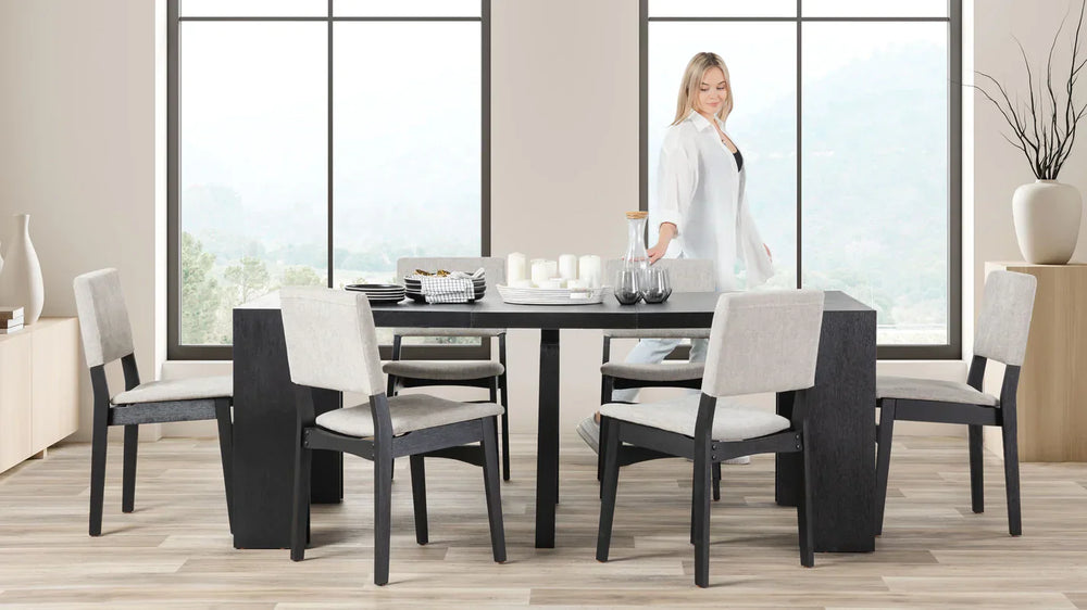 A lady standing at a dark extendable table.